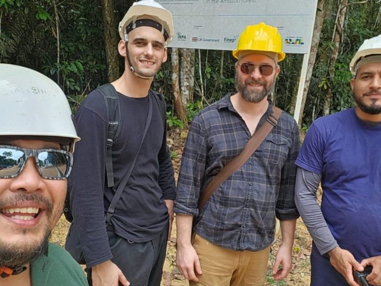 Five people stood together in the Amazon rainforest. They are all wearing hard hat.